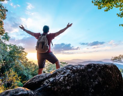 rear-view-back-young-asian-hiking-man-standing-riseup-hands-with-happy-peak-rocky-mountain
