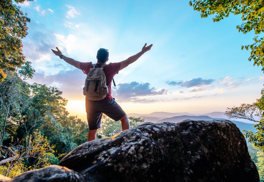 rear-view-back-young-asian-hiking-man-standing-riseup-hands-with-happy-peak-rocky-mountain