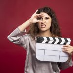 A women holding a clapperboard making faces