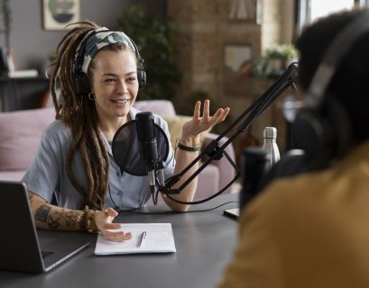 A women part of a podcast sitting in front of a mic smiling
