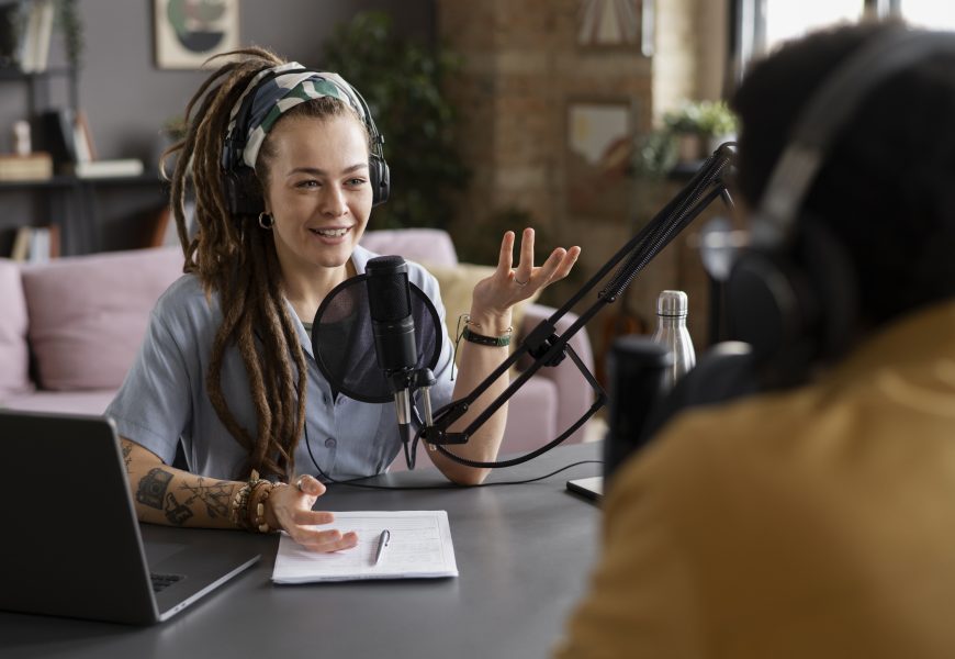 A women part of a podcast sitting in front of a mic smiling