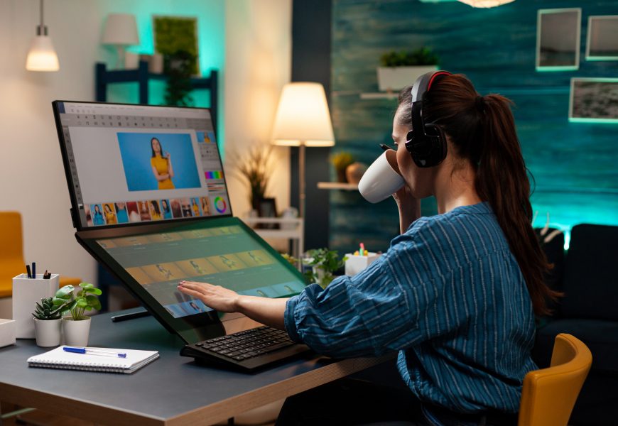 A animation artist women working on a laptop sipping coffee with headphones on
