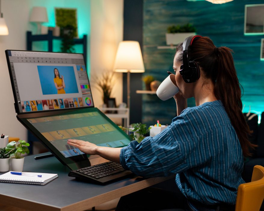A animation artist women working on a laptop sipping coffee with headphones on